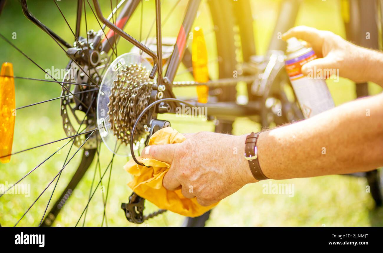 Senior man hand cleaning the bike by spray and rag, doing maintenance
