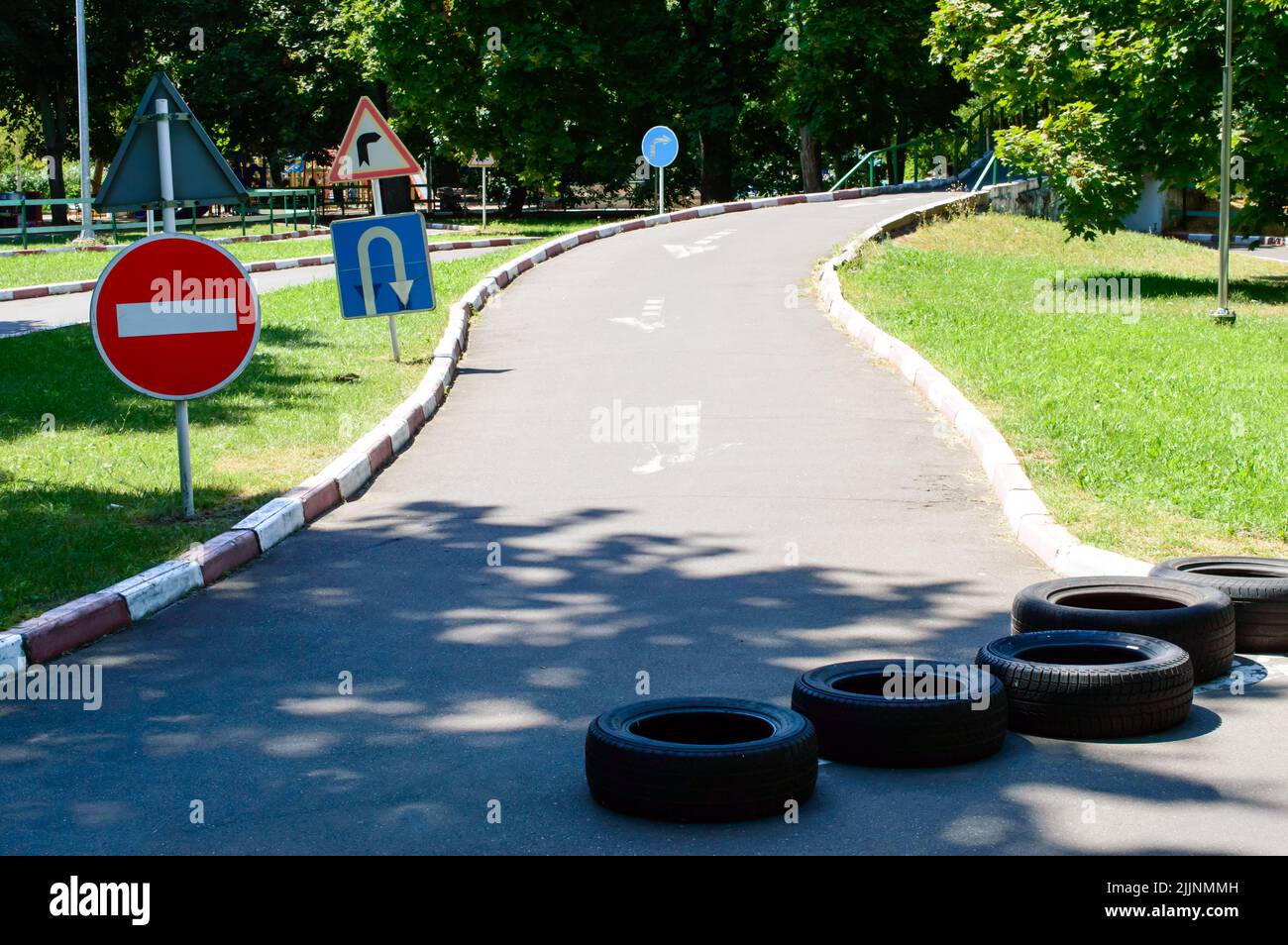 Road signs - no entry, reversal, turn right. Rubber tires on the road.  Autodrome in the park. Stock Photo