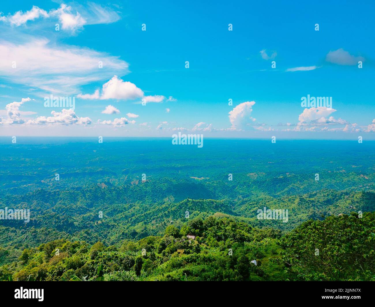 An aerial view of the green mountains gleaming under the cloudy blue ...