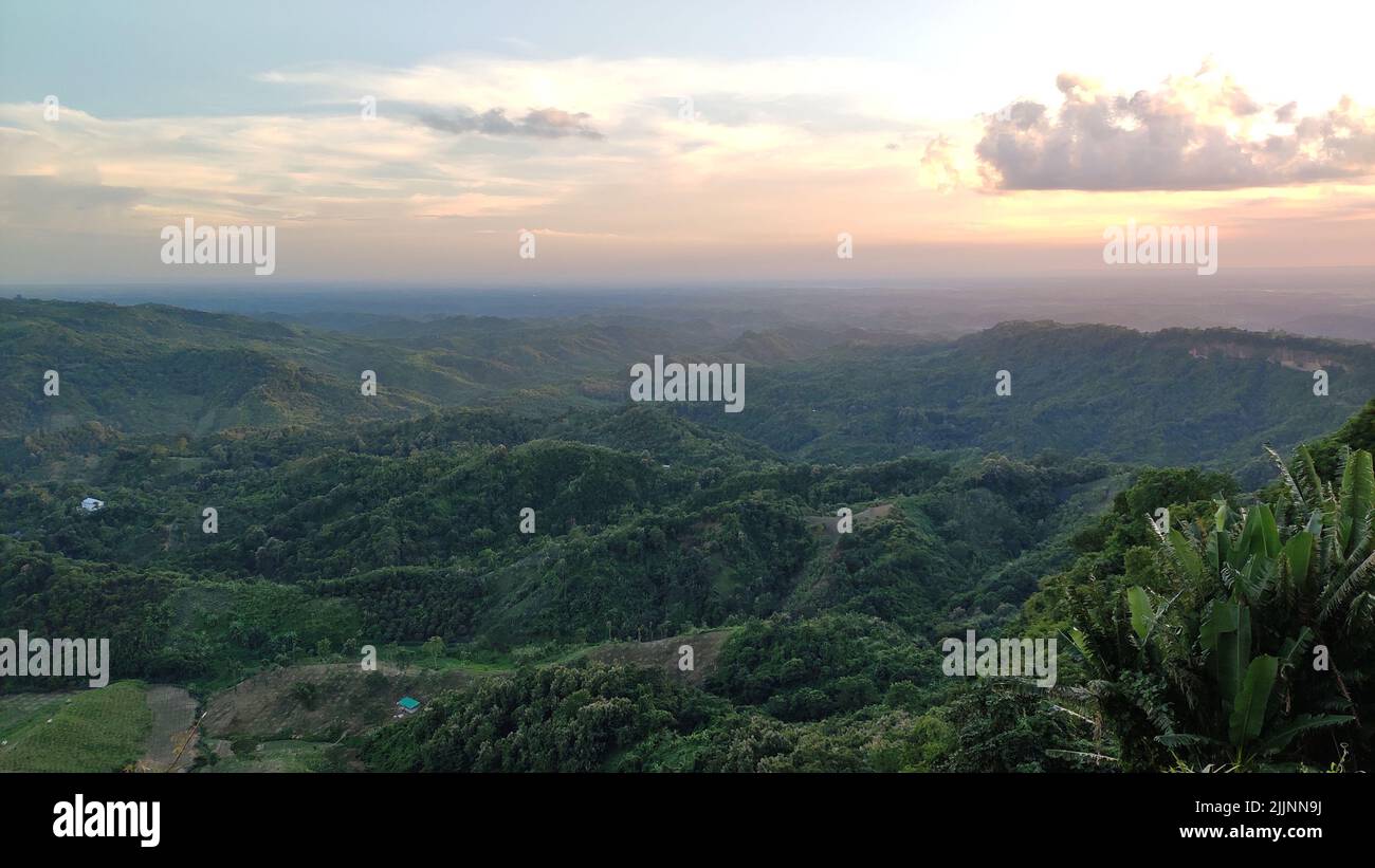 An aerial view of the green mountains gleaming under the cloudy blue ...