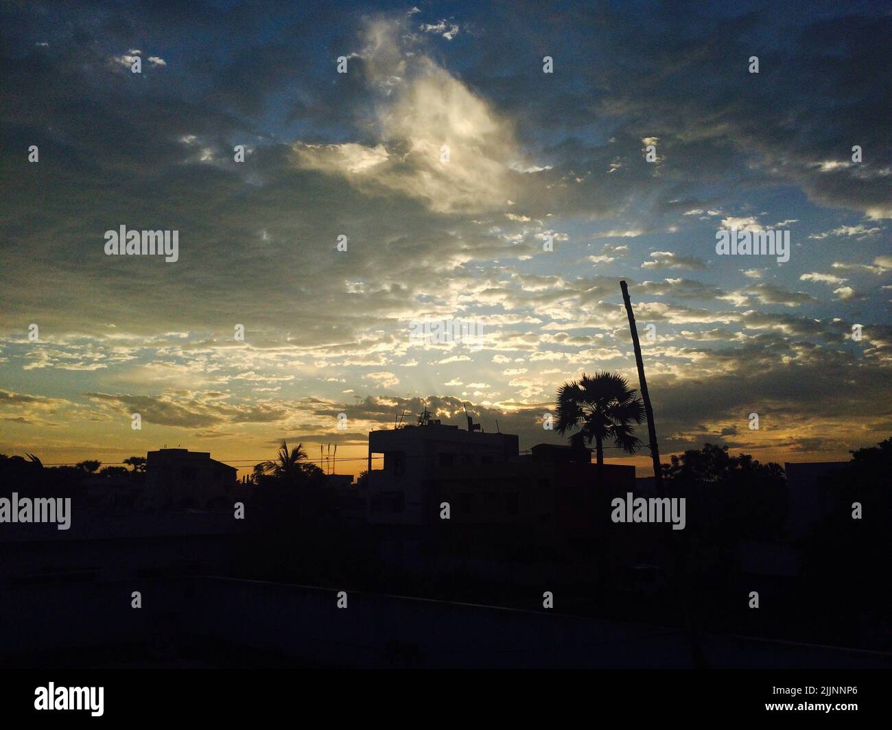 A view of the silhouettes of buildings and trees under the sky with ...