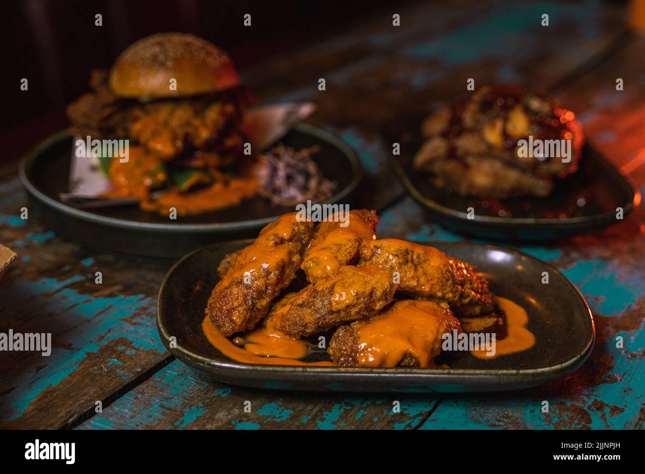 The chicken burger and wings in a dark grungy restaurant setting Stock