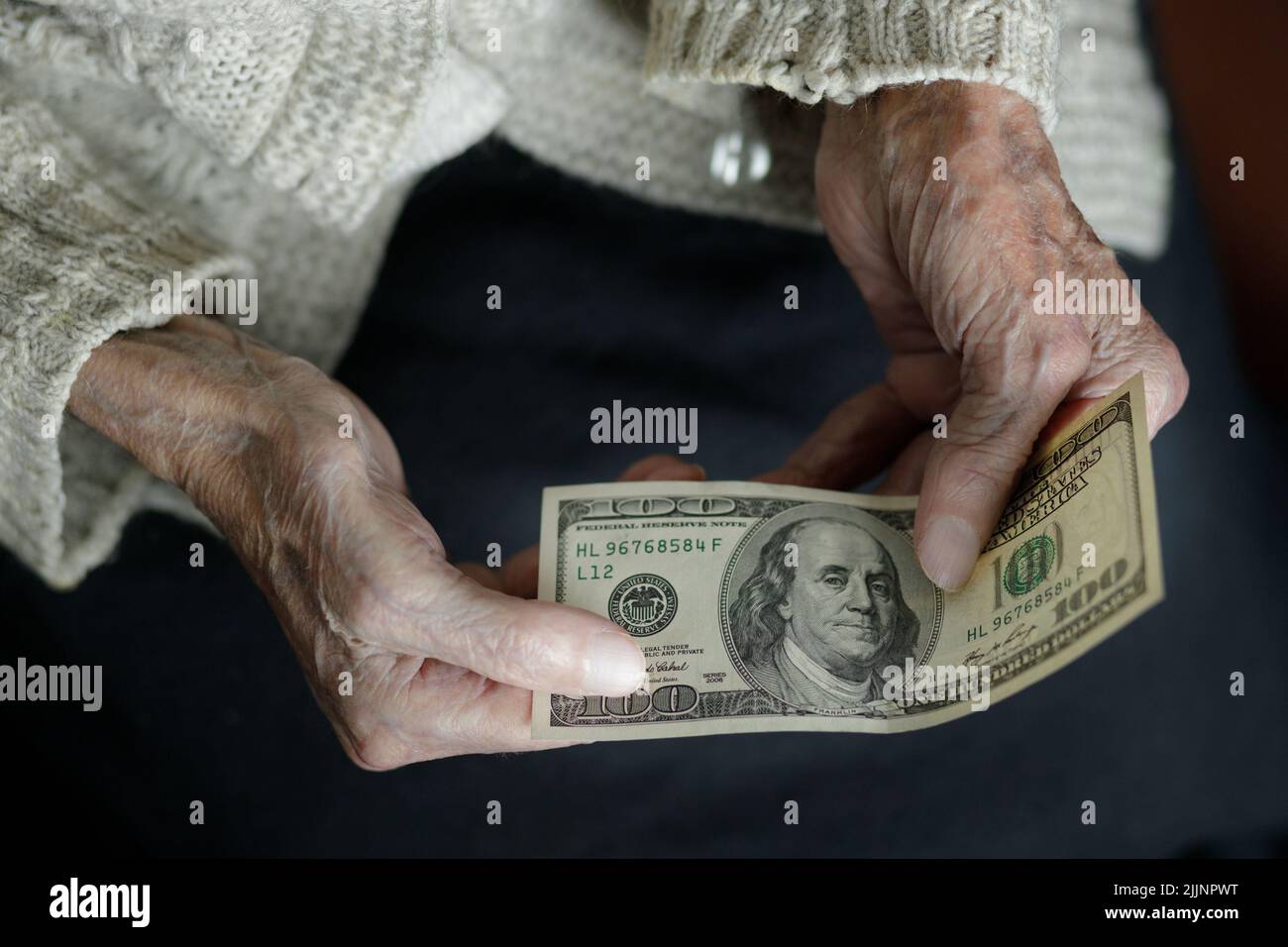 Female hands hold one hundred US dollars. Pension, poverty, social problems and the topic of old age. preservation. Stock Photo