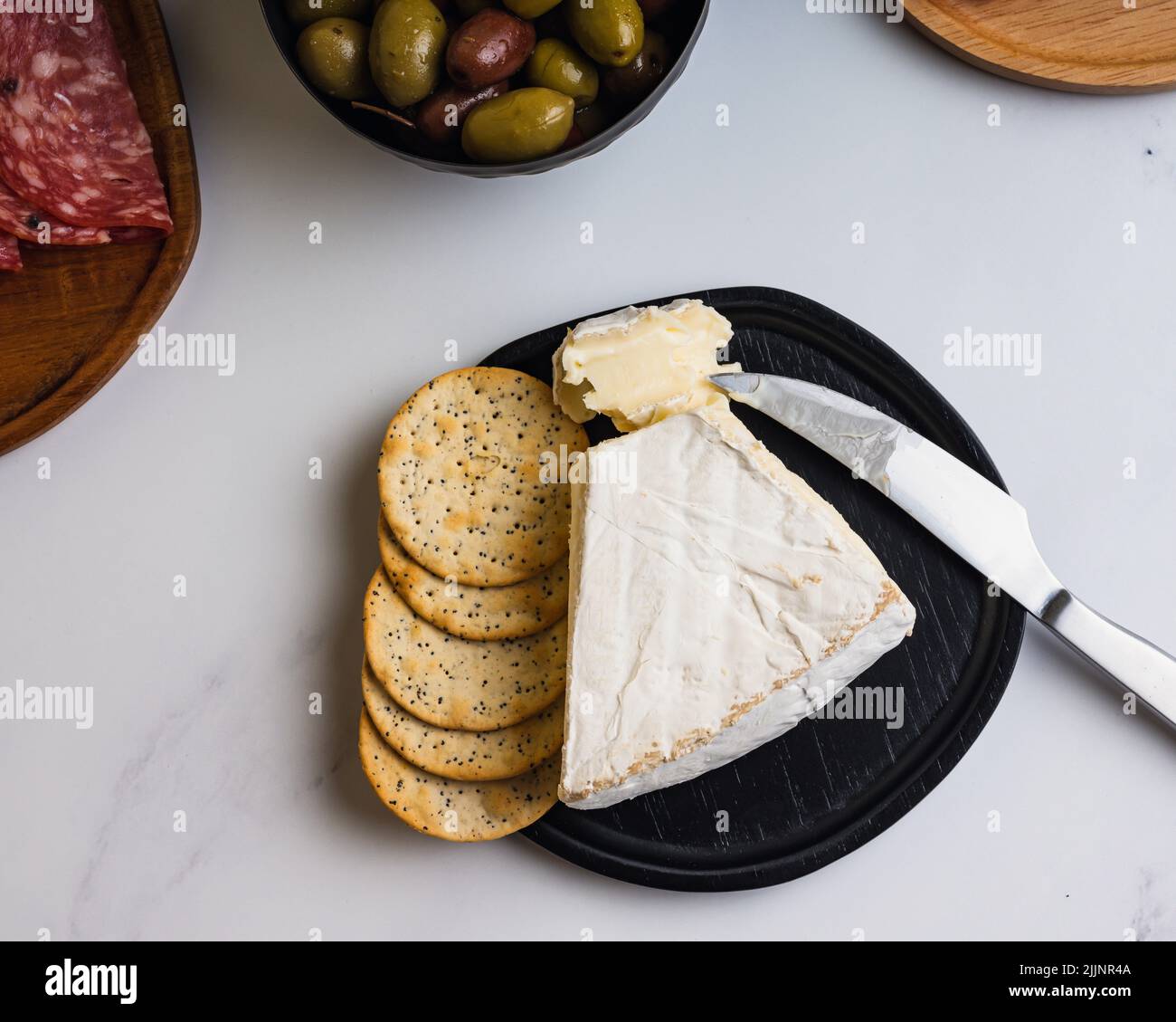 An overhead shot of brie cheese with crackers on white marble surface