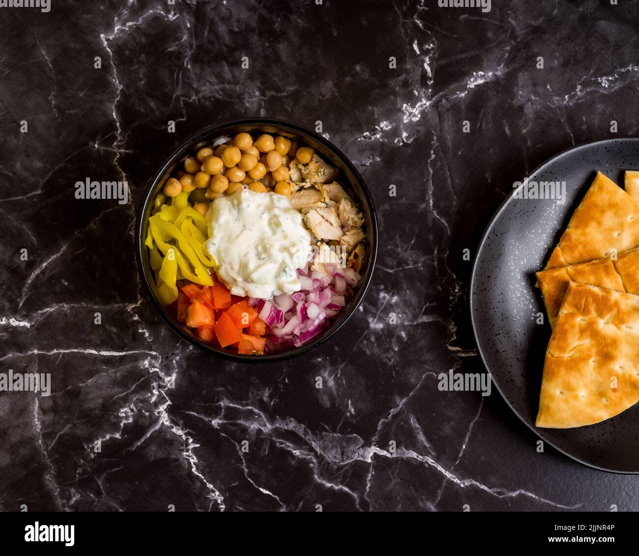 An overhead shot of a Greek-inspired bowl on black marble surface Stock Photo