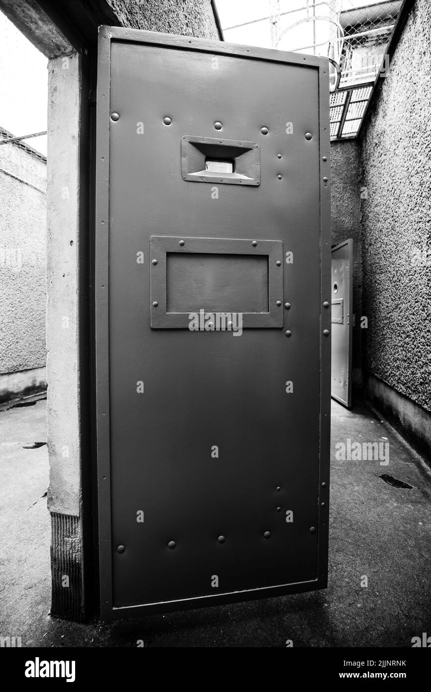 A vertical grayscale shot of an iron door in a mysterious abandoned
