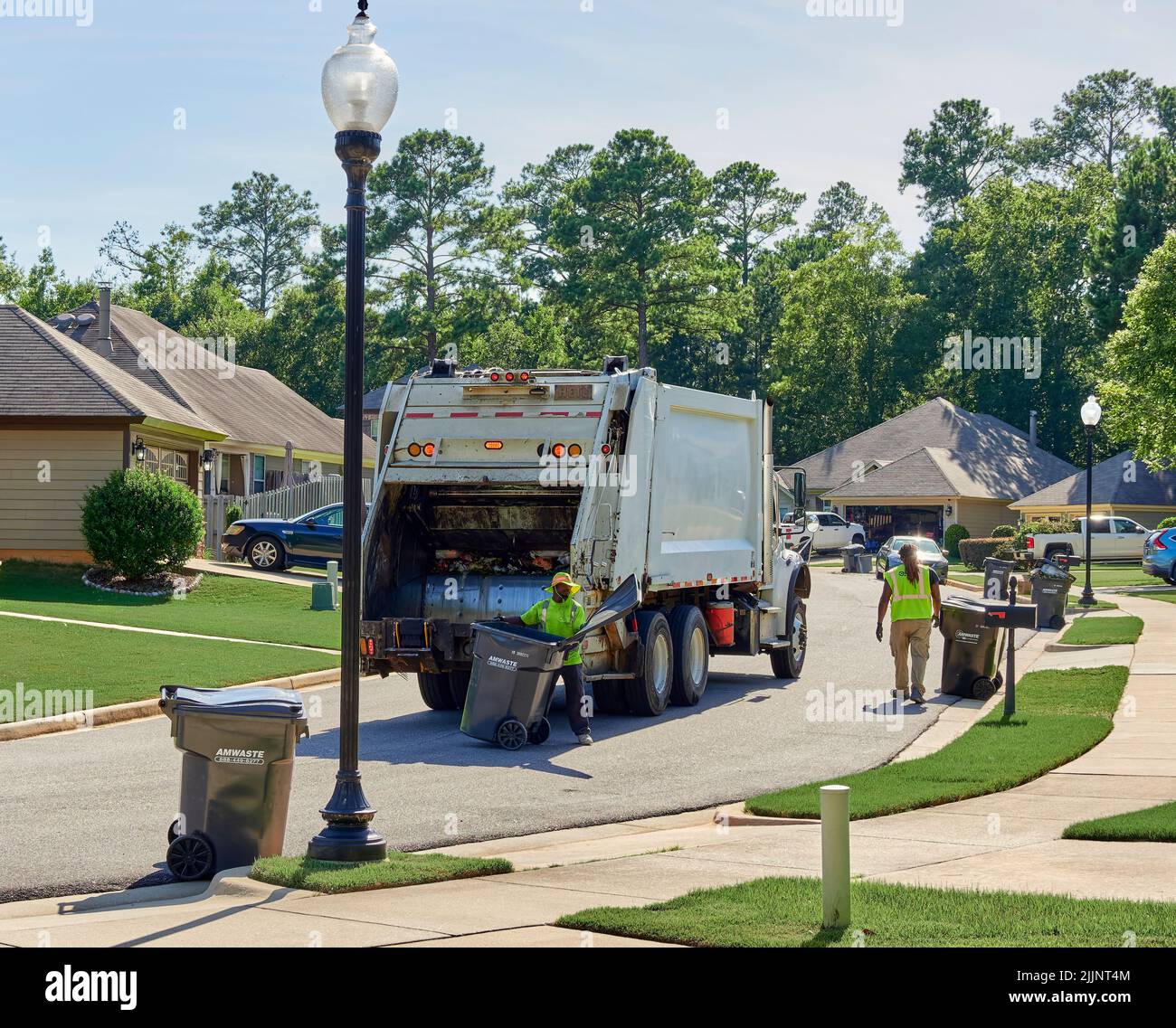 Garbage truck and garbage men picking up the trash in a residential neighborhood in Pike Road Alabama, USA. Stock Photo