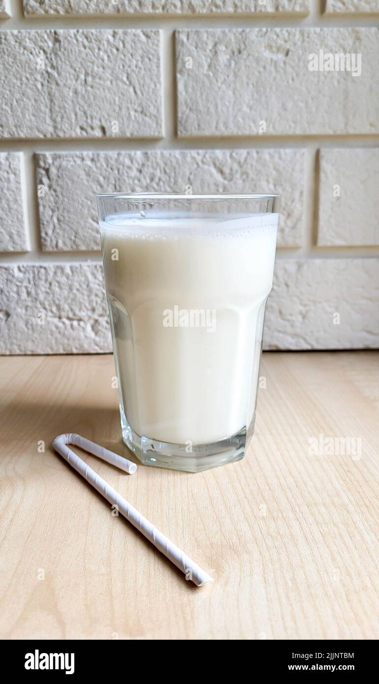 A glass of kefir on the table with a paper tube. Stock Photo