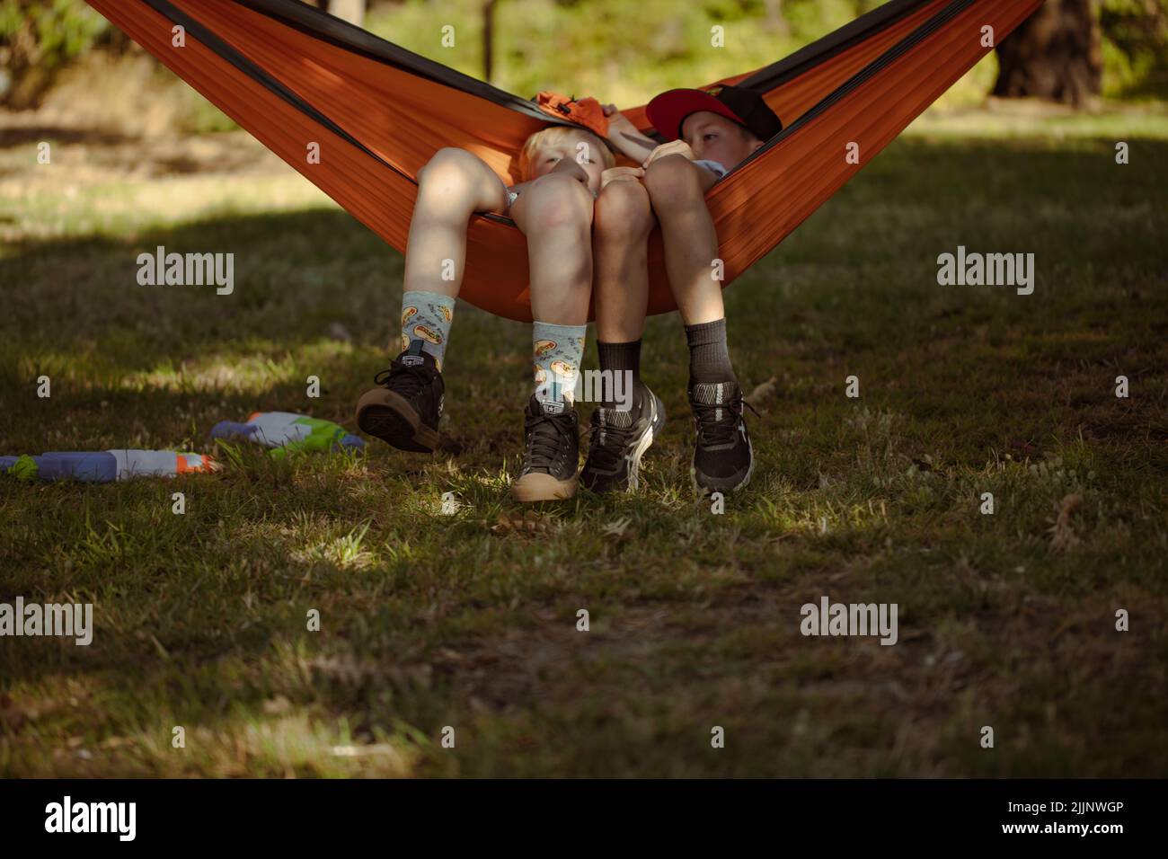 Two boys relaxing on hammock while camping in the Australian bush Stock
