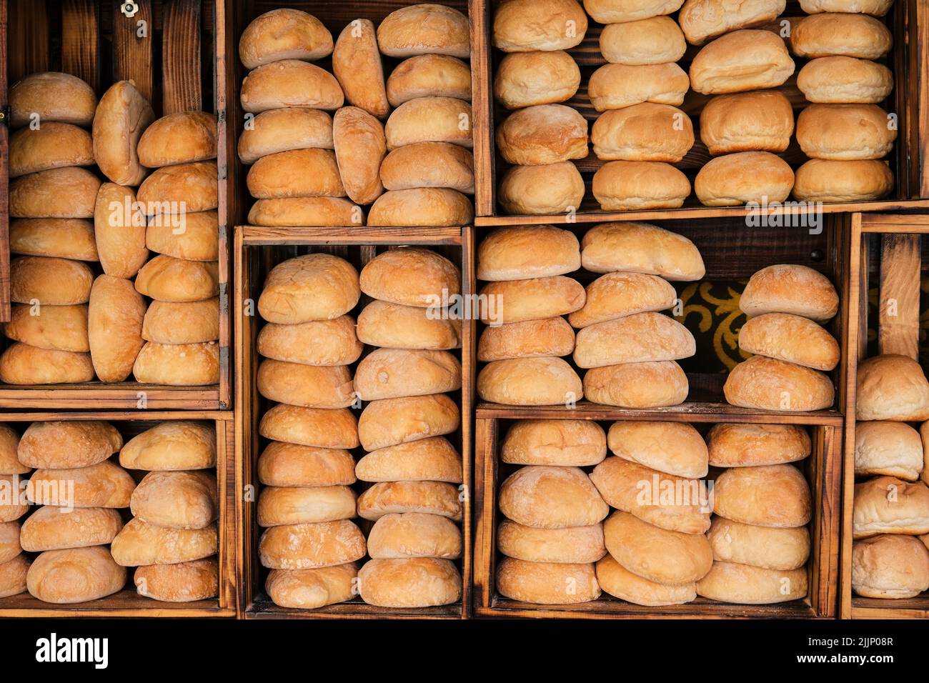 Loaves of freshly baked bread placed on wooden shelves in bakehouse at ...