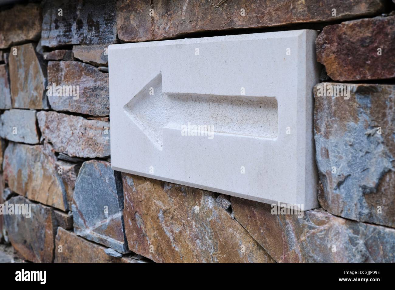 Marble panel with carved arrow installed in wall of stone building on street Stock Photo