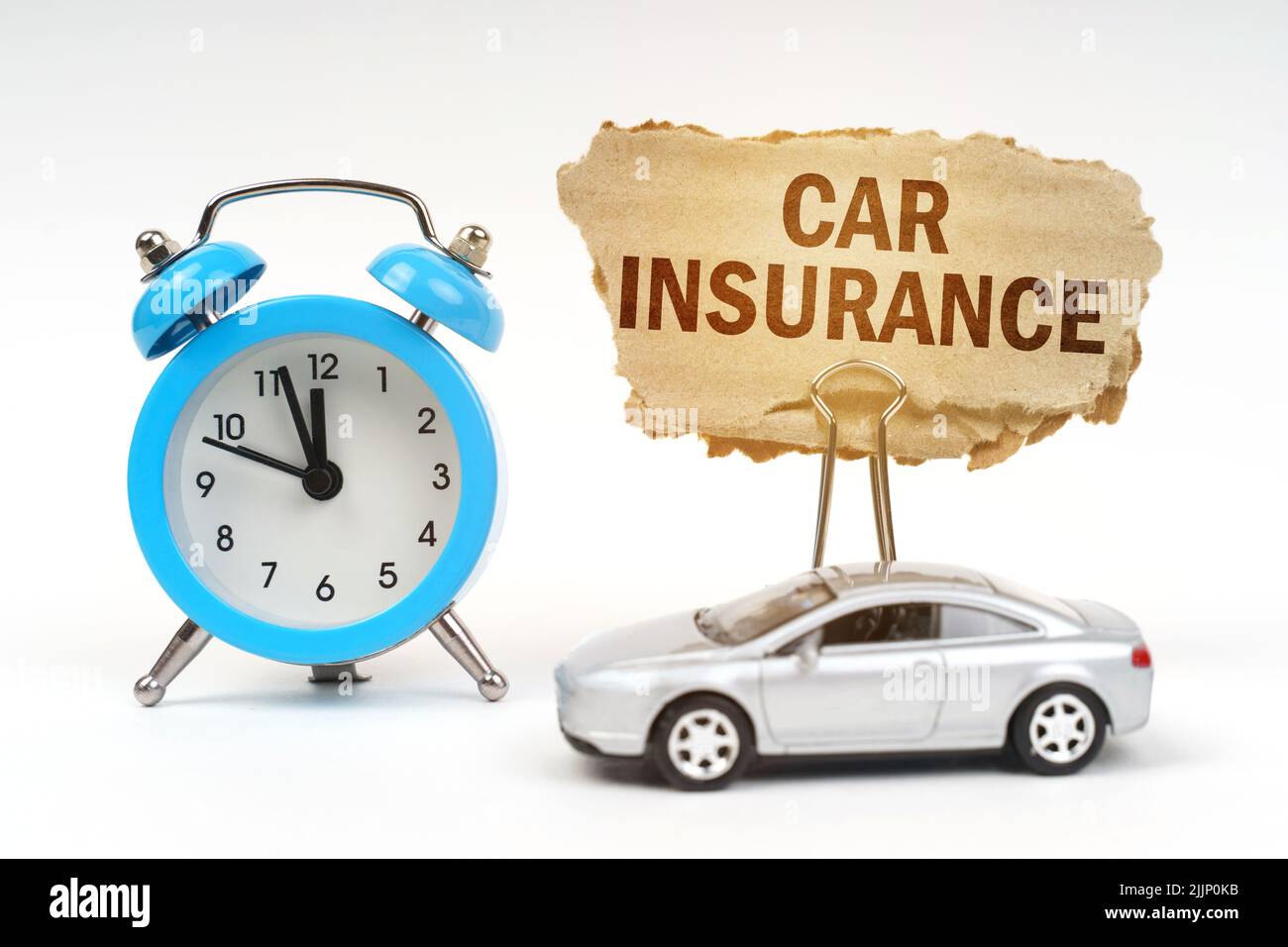 Transport concept. On a white surface there is a blue alarm clock, a car and a sign with the inscription - Car insurance Stock Photo