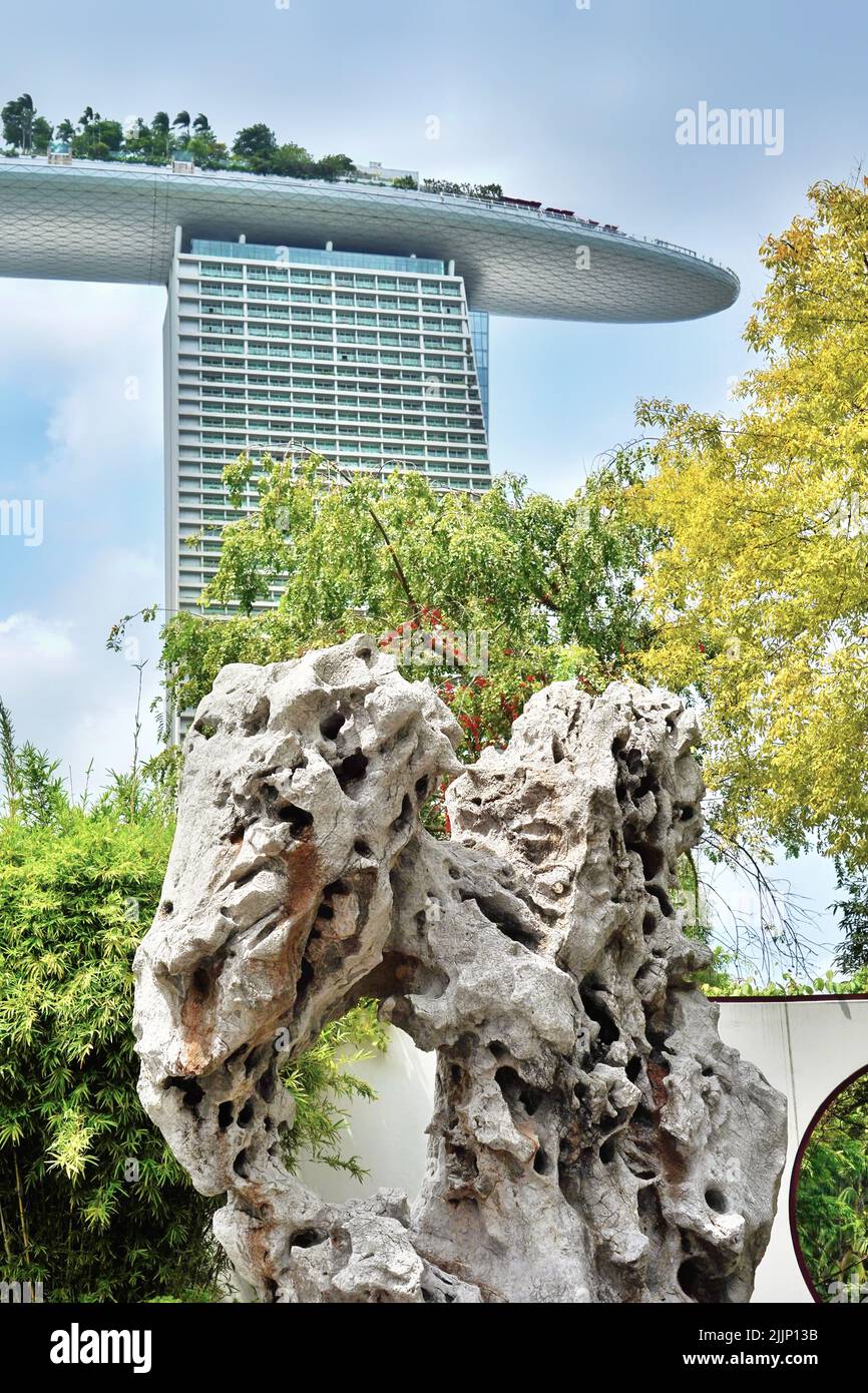 A vertical shot of an abstract rock with the tall Marina Bay Sands hotel in the distance in Singapore Stock Photo