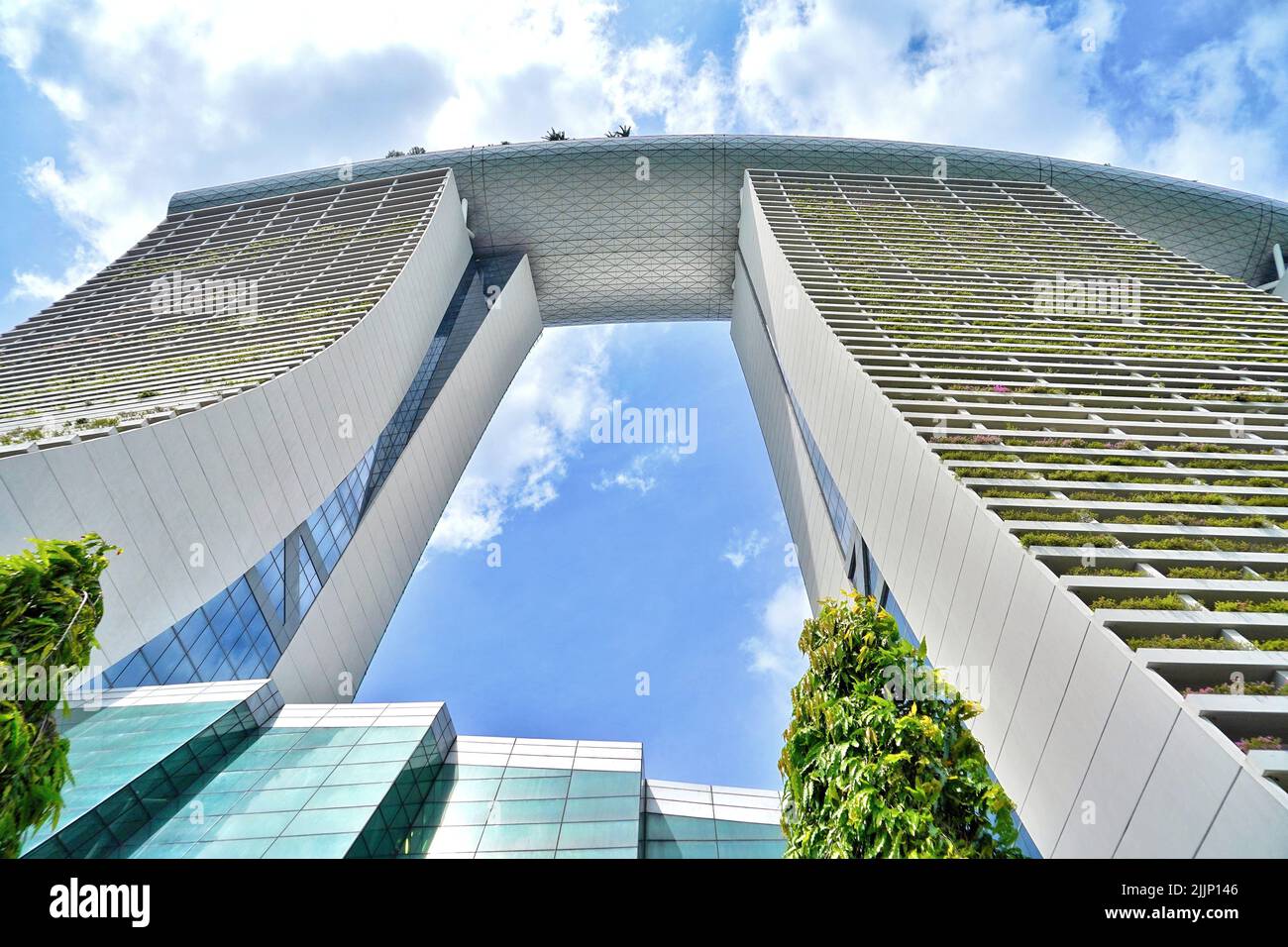 A low angle shot of the tall Marina By Sands hotel in Singapore under a vibrant cloudy summer sky Stock Photo