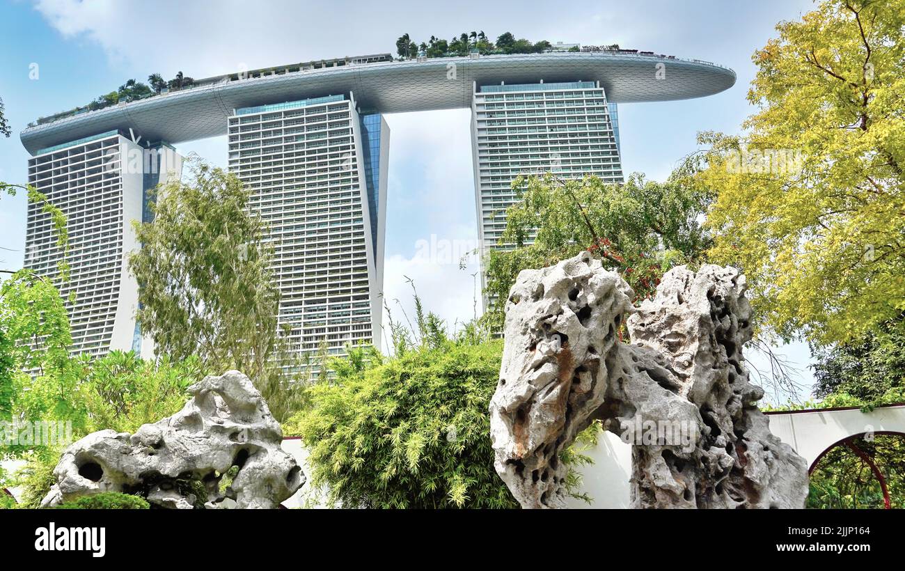 A warm summer day in Singapore with the Marina Bay Sands hotel in the distance surrounded by greenery Stock Photo