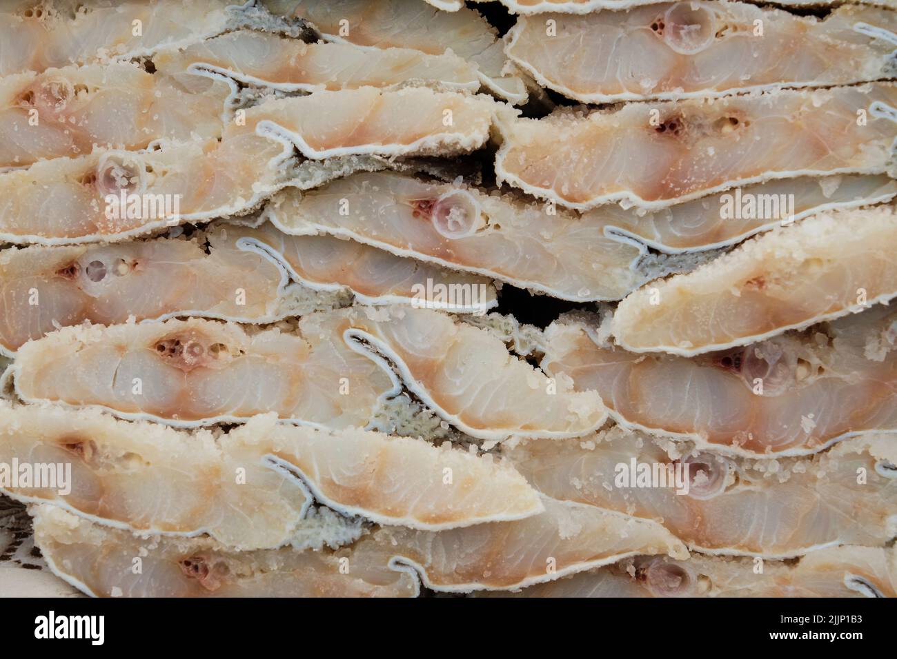 Full frame background of pieces of cod with salt stacked together on stall Stock Photo