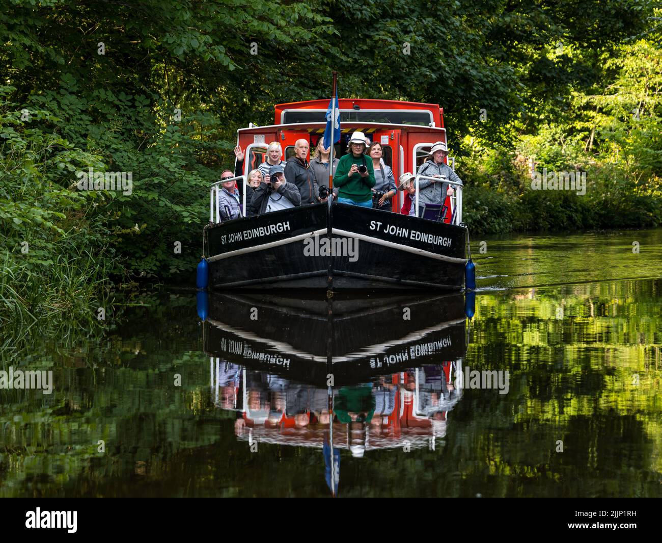 Ratho, Scotland, United Kingdom, 27th July 2022. UK Weather: sunny evening on the Union Canal. A photography group enjoys a cruise along the canal in a narrow boat reflected in the water Stock Photo