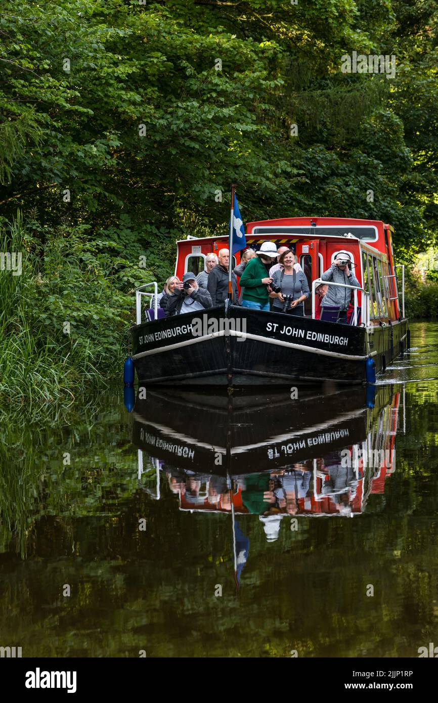 Ratho, Scotland, United Kingdom, 27th July 2022. UK Weather: sunny evening on the Union Canal. A photography group enjoys a cruise along the canal in a narrow boat reflected in the water Stock Photo