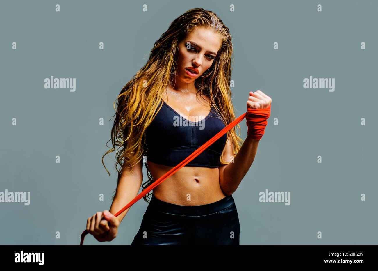 Sport woman preparing for fight. Fighter girl in sports top with red bandages fists. Female boxer. Stock Photo