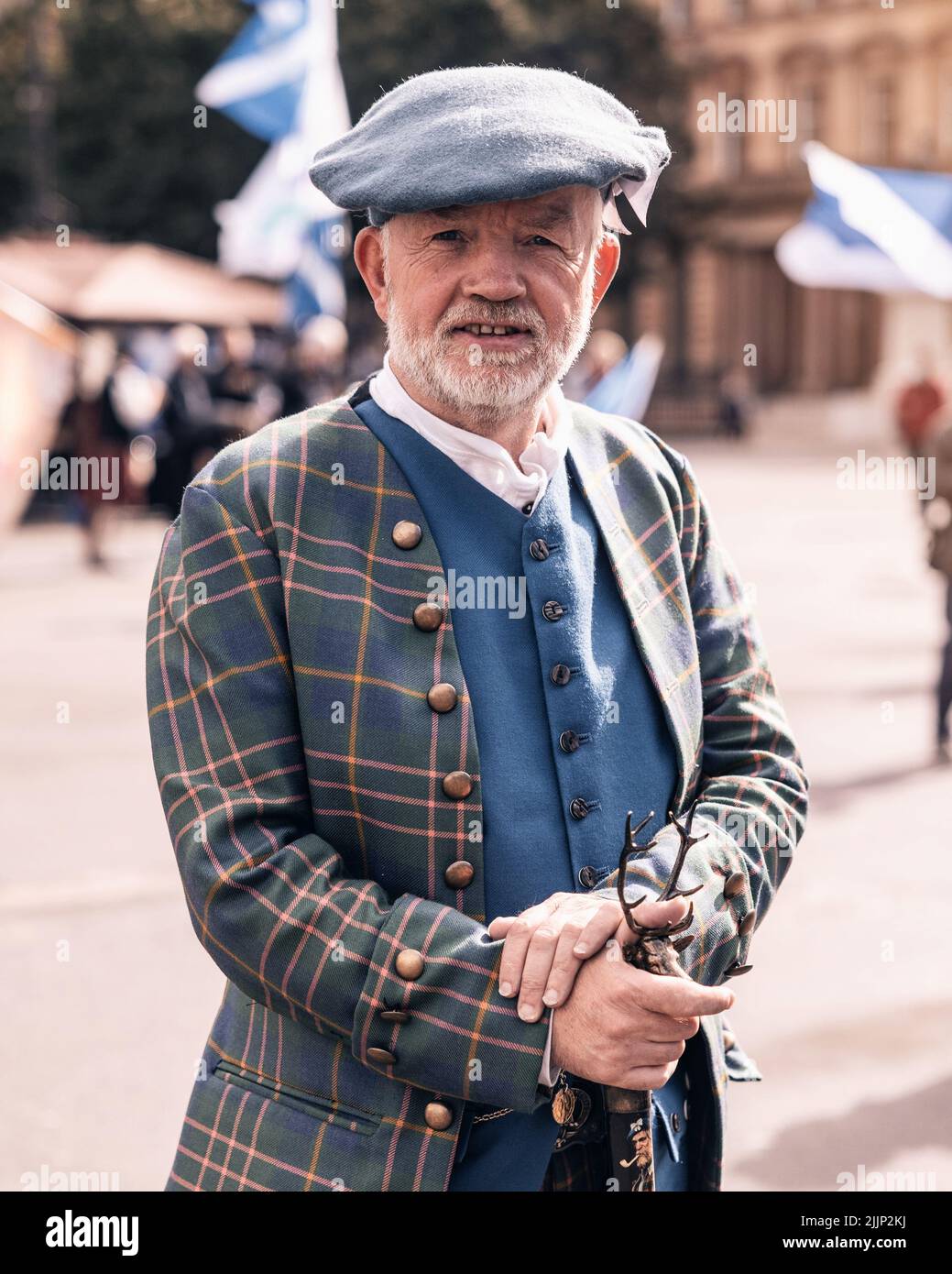 A closeup of a senior Scottish man wearing a tartan jacket and hat in Glasgow, United Kingdom Stock Photo
