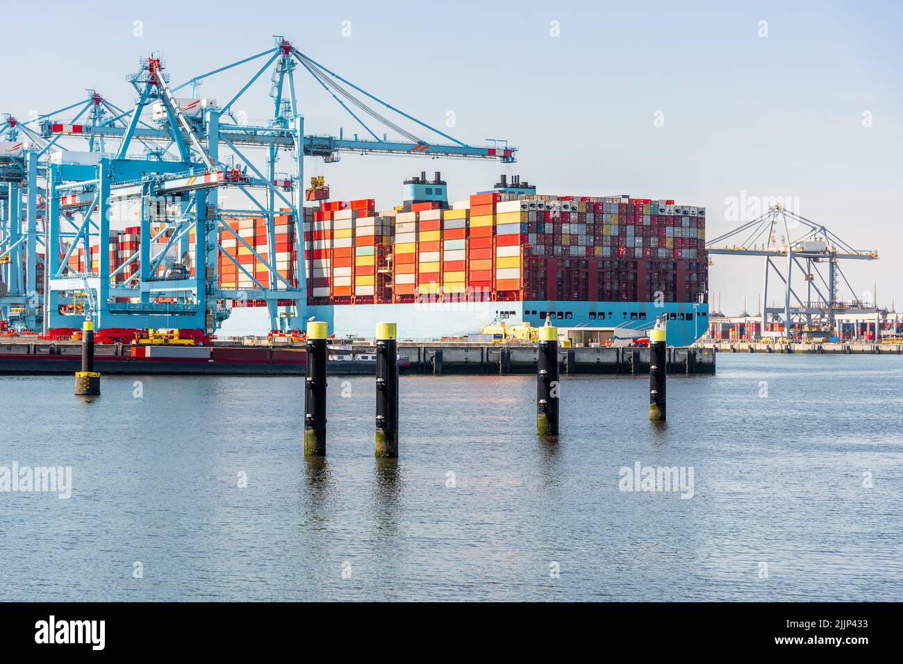 Large container ship being loaded in harbour on a clear summer day Stock Photo