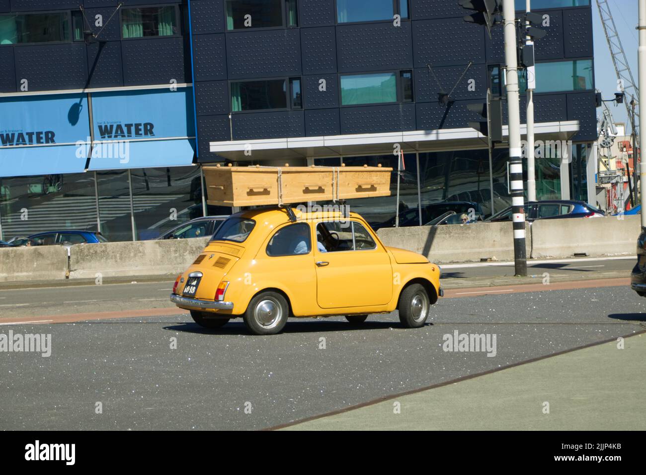 A yellow fiat 500 bambino with a coffin on the roof Stock Photo