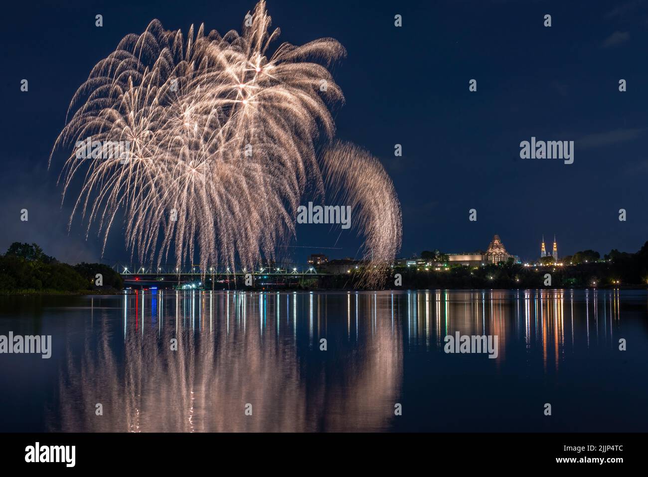 A beautiful view of fireworks in the night sky over the lake by the city Stock Photo