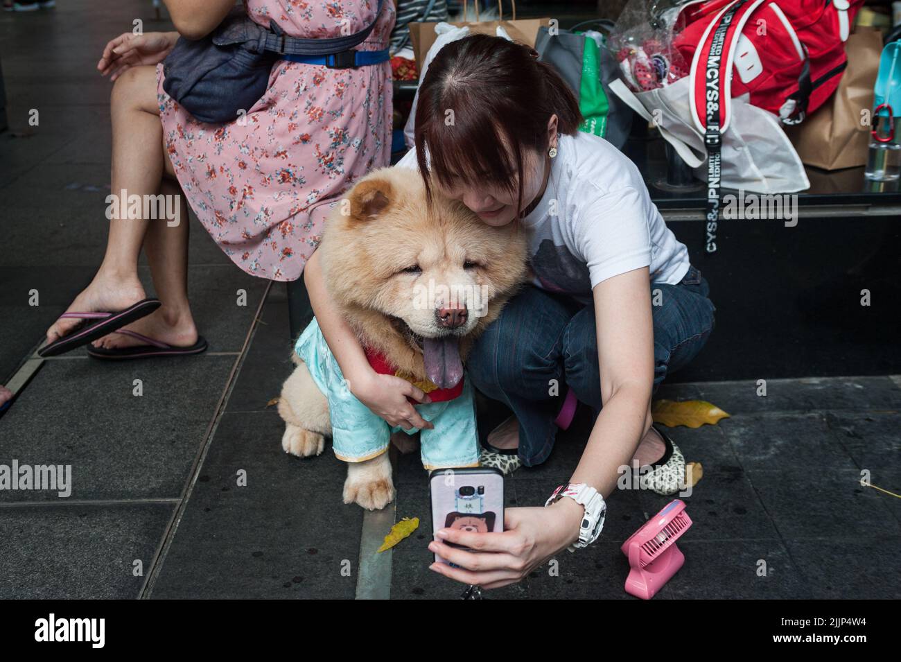 03.02.2018, Singapore, Republic of Singapore, Asia - Woman takes selfie together with her dog, a Chow Chow, at the Kreta Ayer Square in the Chinatown. Stock Photo