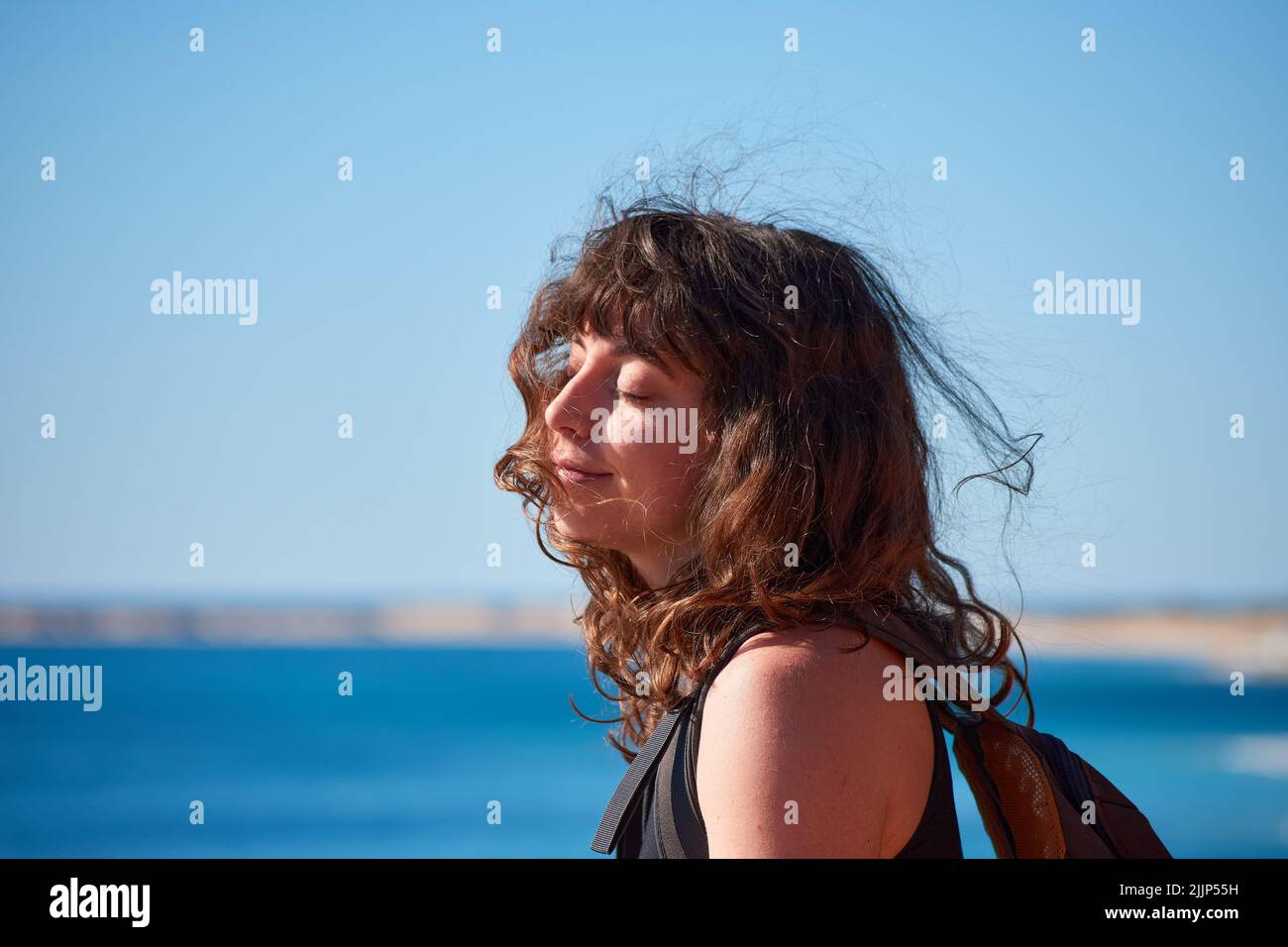 A shallow focus of a beautiful smiling Caucasian brunette female against the blue sky Stock Photo