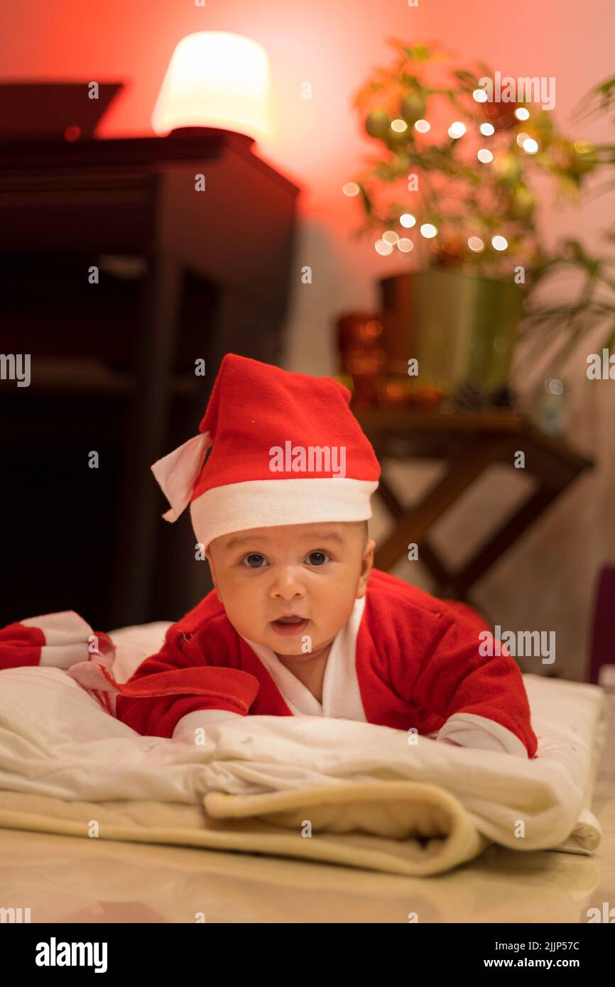 A vertical shot of an Indian kid wearing a Santa costume. Stock Photo