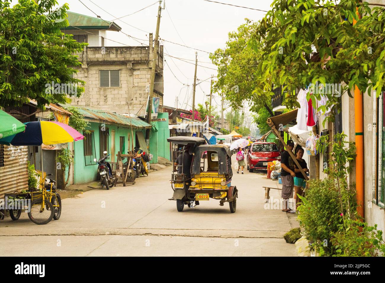 A view of tricycle taxi on the Philippines road surrounded by old houses and shops Stock Photo