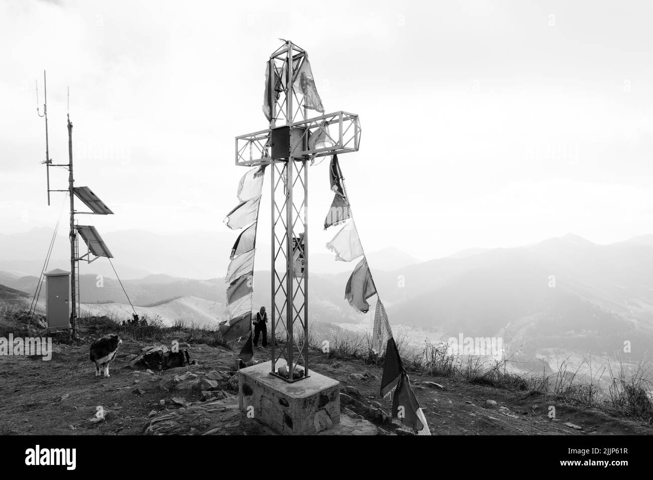 A grayscale shot of metal cross with bandits on top of the alps mountain in Milano, Italy Stock Photo