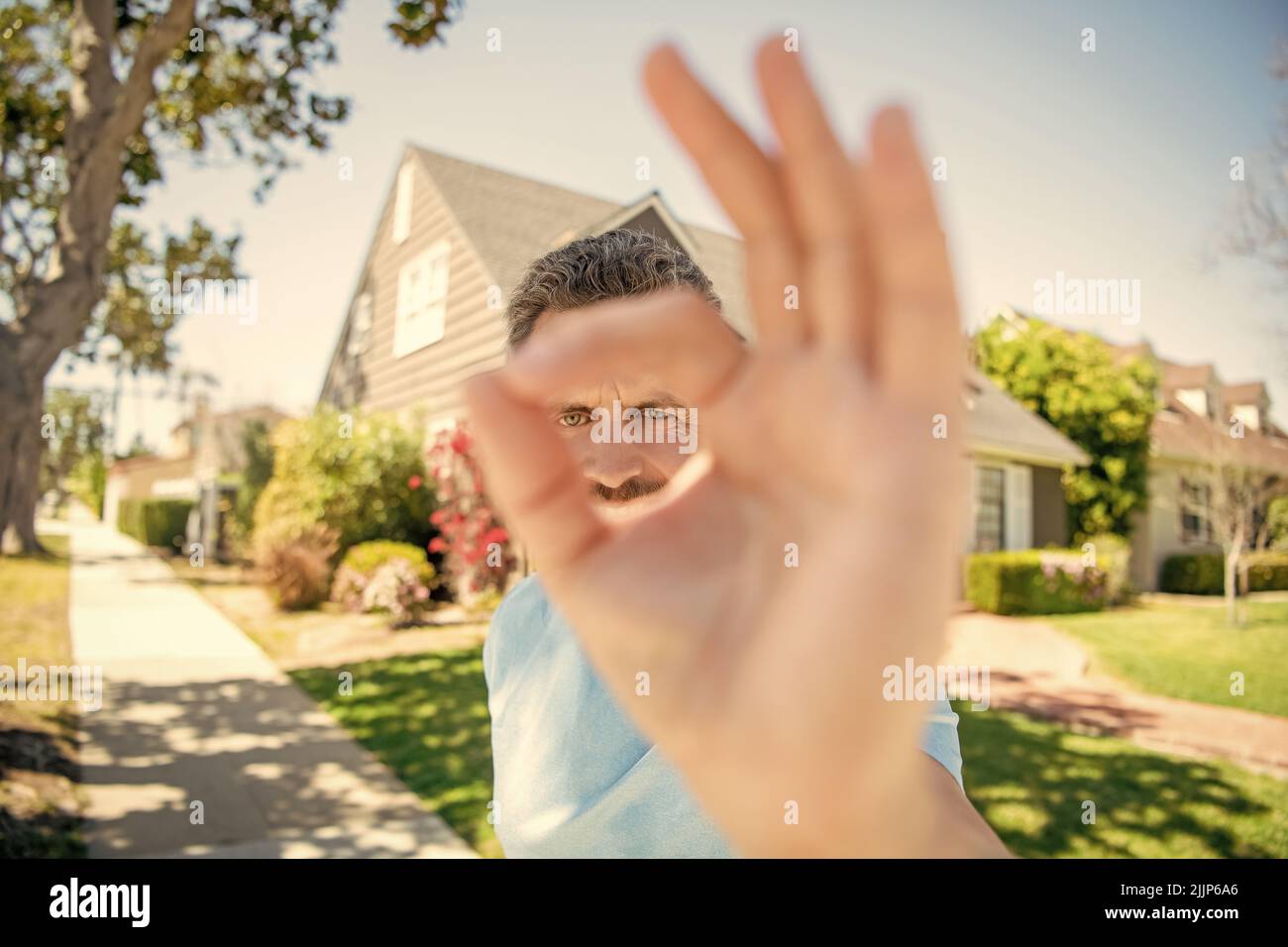 ok gesture. real estate agent at house for sale. realtor welcoming visitors. Stock Photo