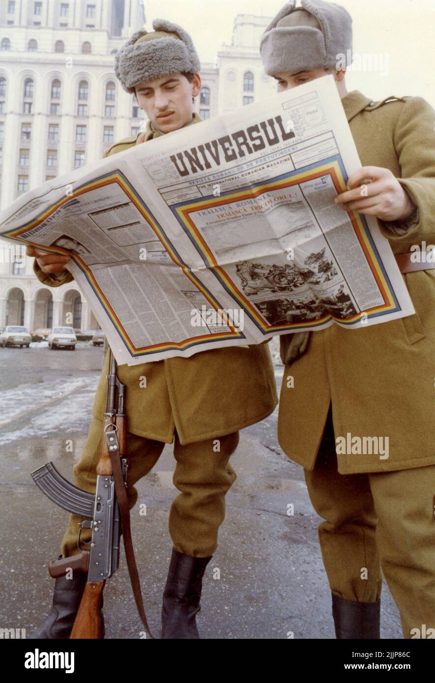 Bucharest, Romania, January 1990. Days after the Romanian Revolution, soldiers in front of 'Casa Scanteii/ Casa Presei Libere' looking over the 'Universul' magazine. 'Universul' was published in the United States by A. Buhoiu for the Romanians in the U.S.A. There was a thirst for information in Romania, especially for the one coming from outside the country. Stock Photo