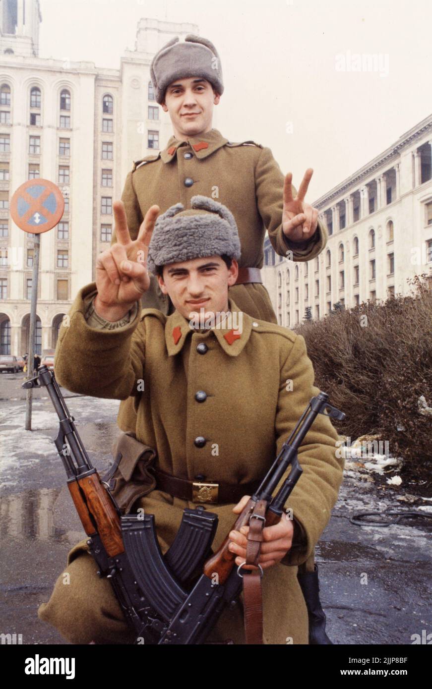 Bucharest, Romania, January 1990. Days after the Romanian Revolution, soldiers in front of 'Casa Scanteii/ Casa Presei Libere' making the victory sign. Stock Photo