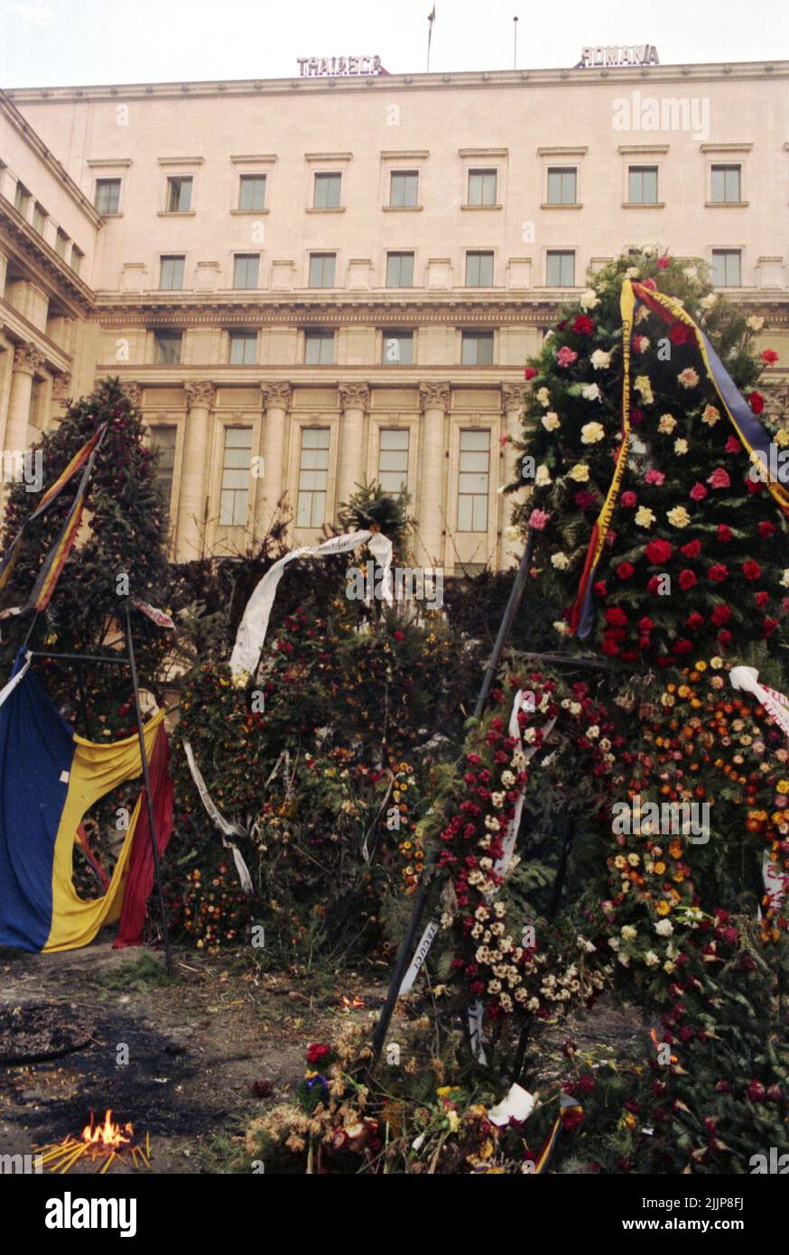 Bucharest, Romania, January 1990. Flowers in Piata Palatului/ Piata Revolutiei for the victims of the anticommunist revolution of December 1989. On top of the governmental building, one can read 'Long live Romania', after the removal of the in- between words 'the Socialist republic of '. Stock Photo