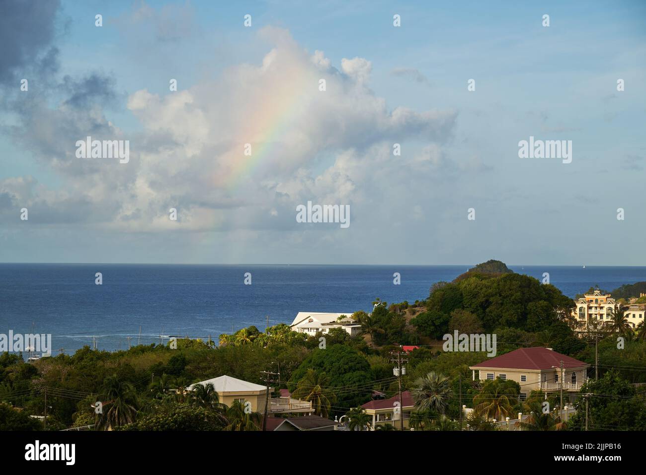 A beautiful view of a small rainbow on the clouds above the sea near a ...