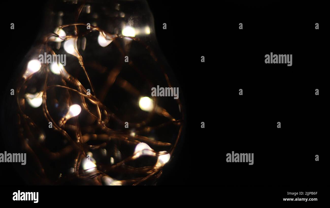 A led fairy lights inside a bulb isolated on a dark background Stock