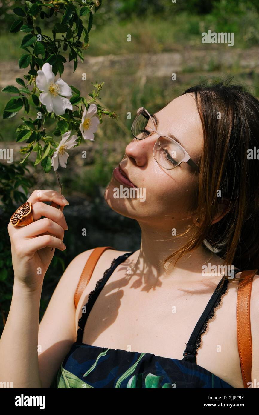 A multi-racial Beautiful woman with eyeglasses golding Rosa laevigata flowers in spring outdoors Stock Photo