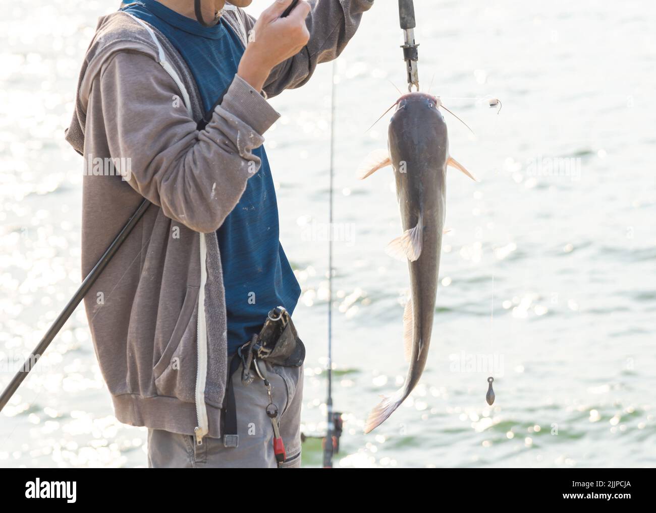 A close-up shot of a fisherman with a rod and a fish lip gripper catching the catfish near Lavon Lake, Texas, America Stock Photo