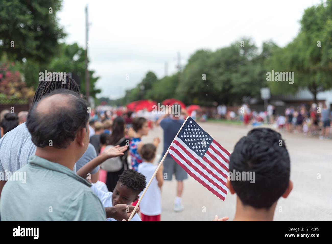 Diverse people waving American flags watching street parade on July 4th ...