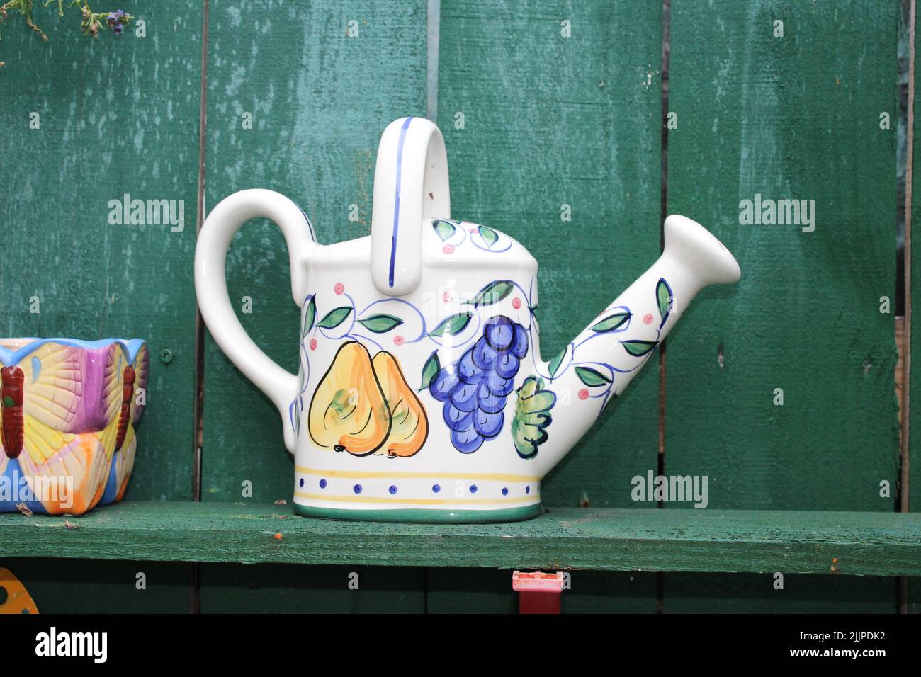 A kettle for watering the flowers with colorful decorations on a wooden surface Stock Photo