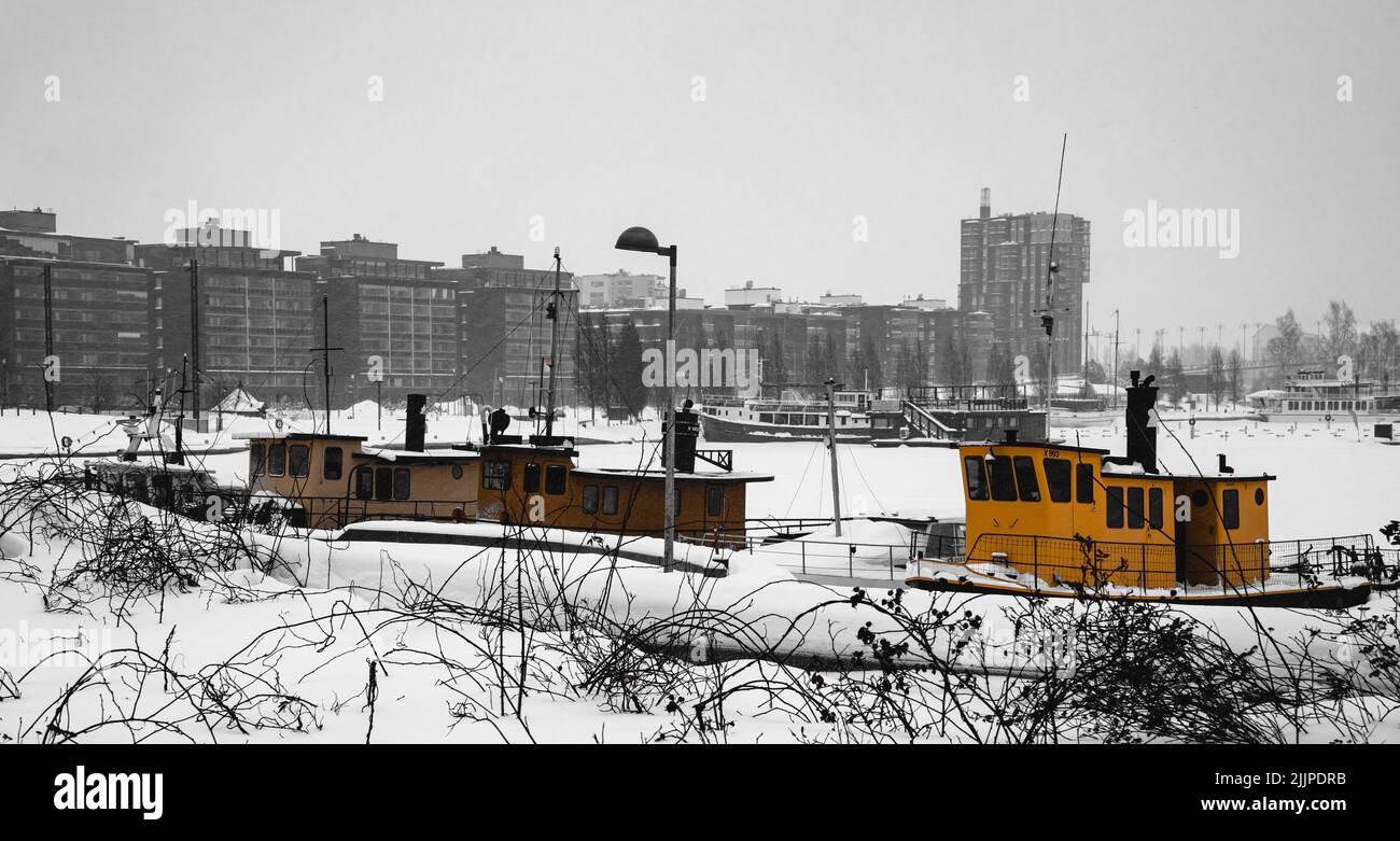 A view of boats in the frozen lake and small bright shelters in the foreground in Jarvenpaa, Finland Stock Photo
