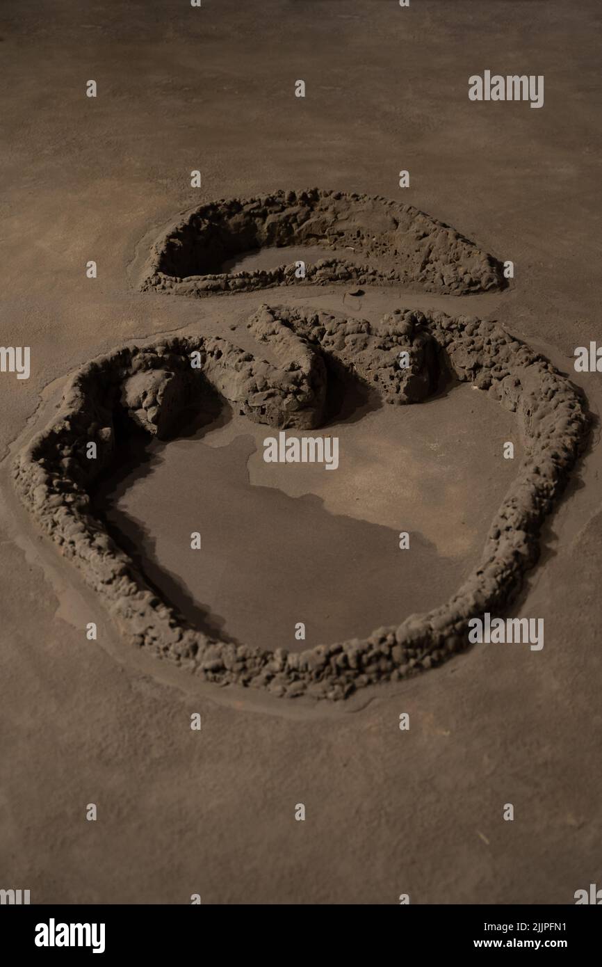 A vertical shot of a dinosaur footprint on mud Stock Photo