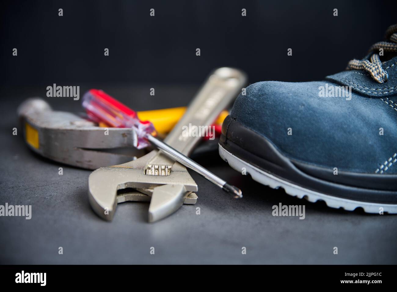 A closeup of metal tools placed next to a blue suede boot on a blurry background Stock Photo