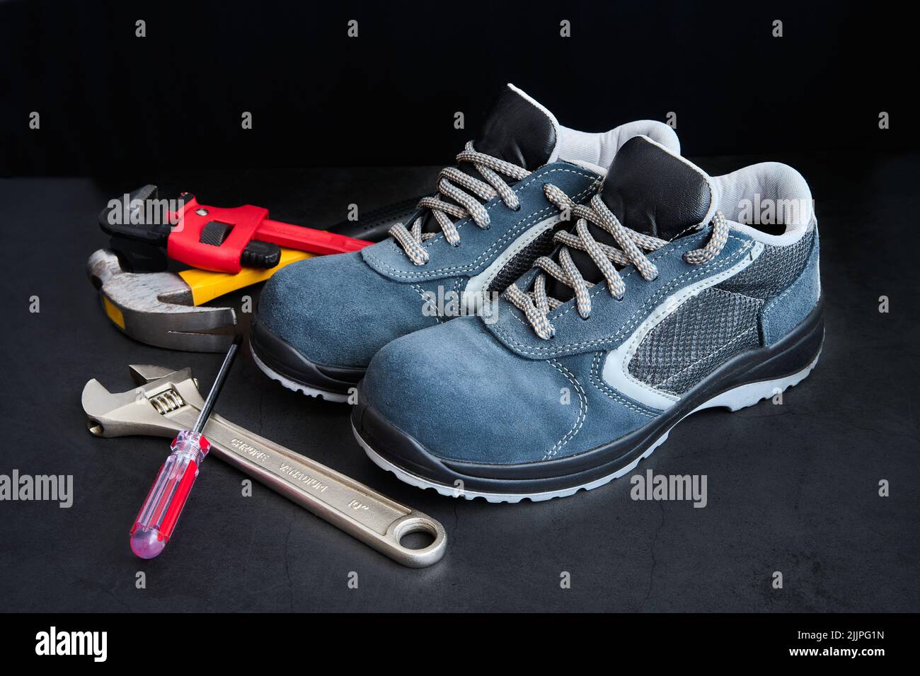 A closeup of male construction worker shoes with metal tools next to it Stock Photo
