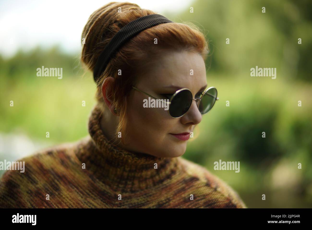 A closeup shot of a female with ginger hair, round, sunglasses, and a turtleneck posing Stock Photo