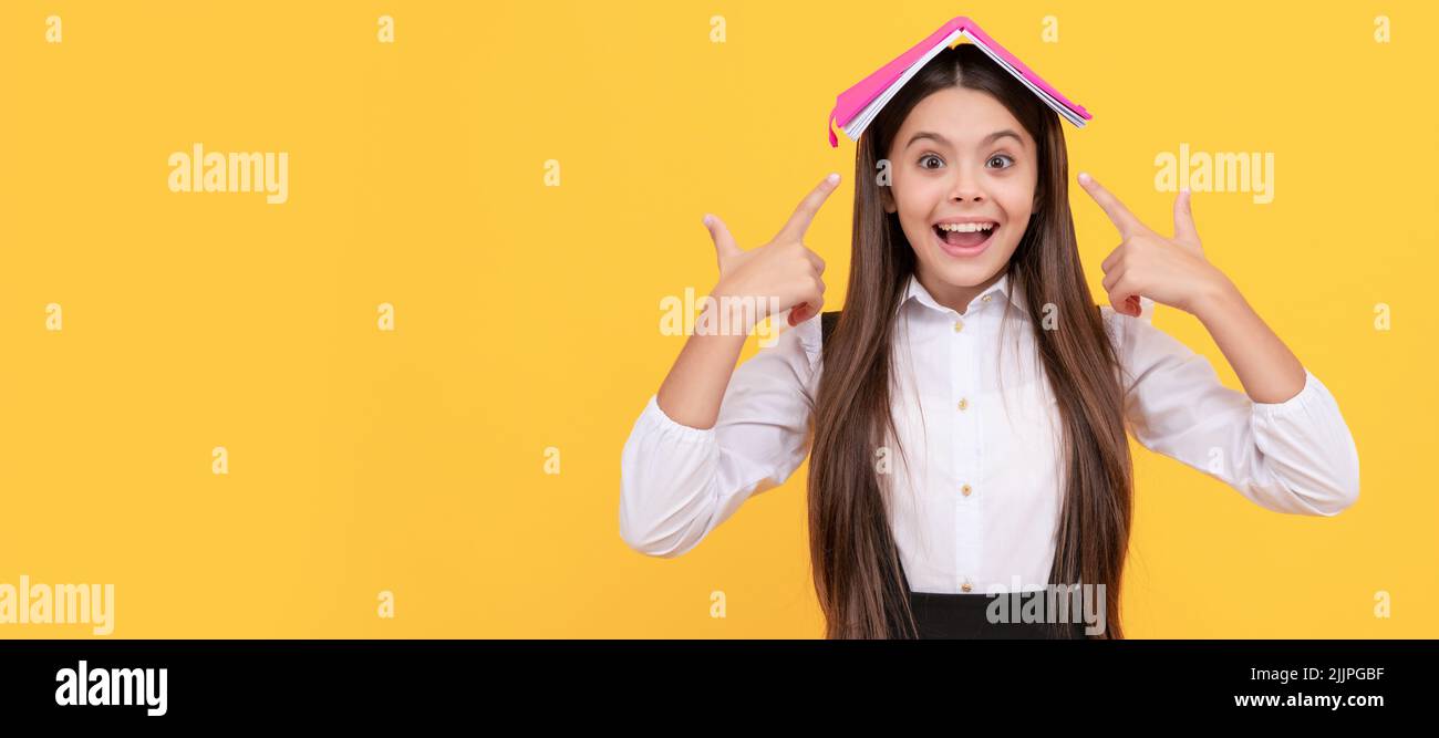 happy teen girl in school uniform pointing finger book on head, learn. Portrait of schoolgirl student, studio banner header. School child face Stock Photo