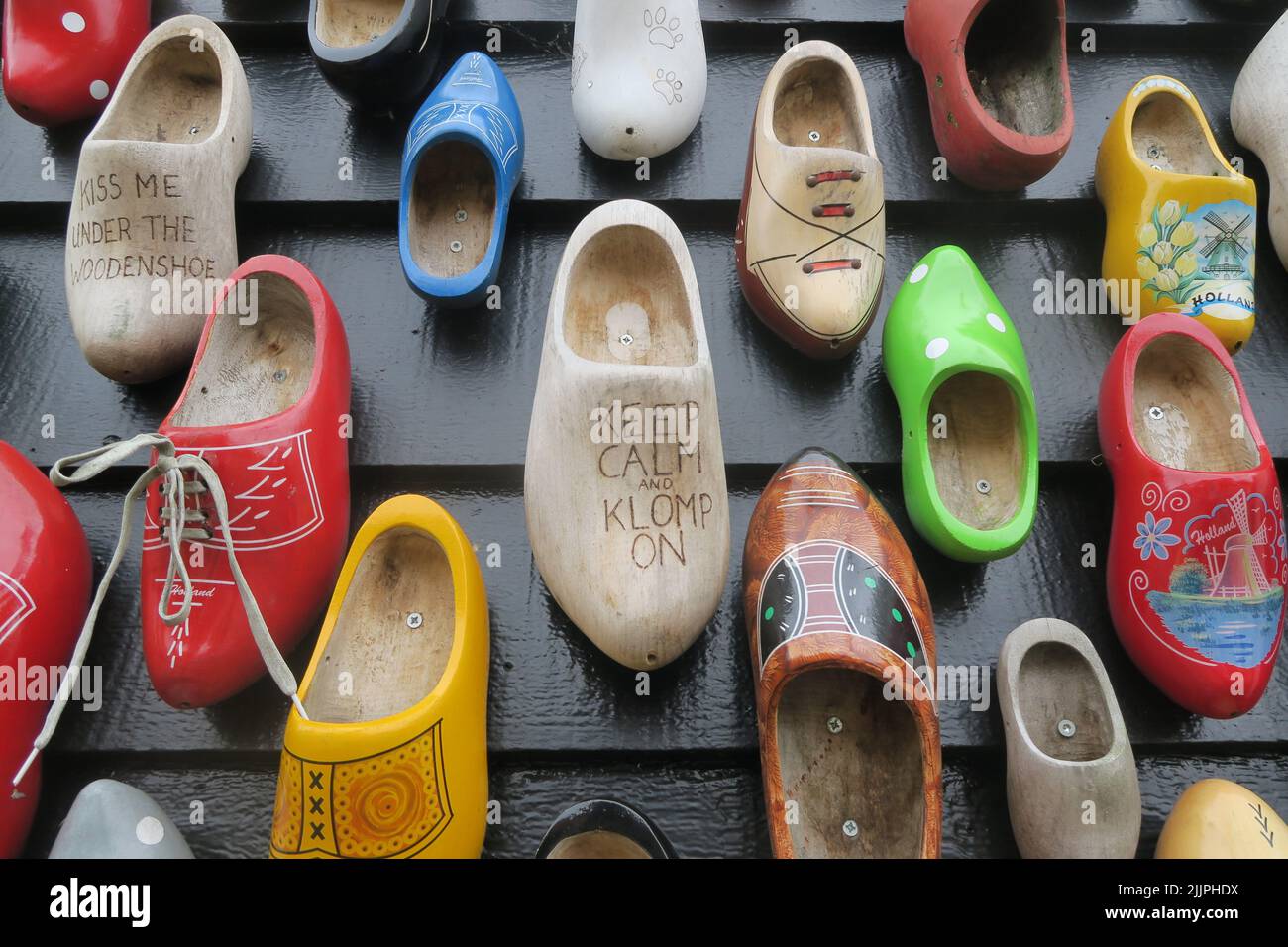 A closeup of multiple clogs in different colors on the wall with sayings Stock Photo