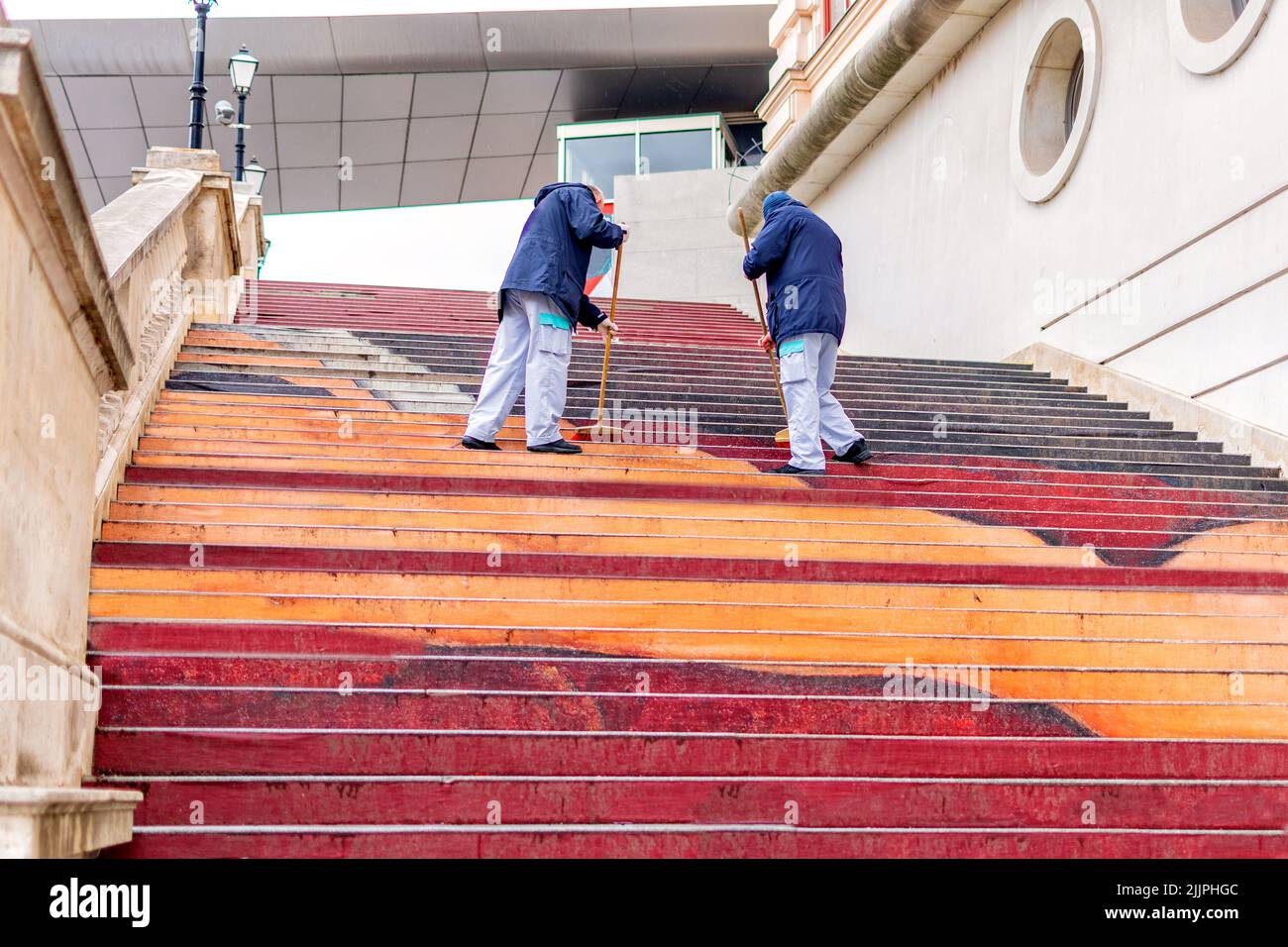 A low angle shot of two street cleaners sweeping public stairs. Stock Photo